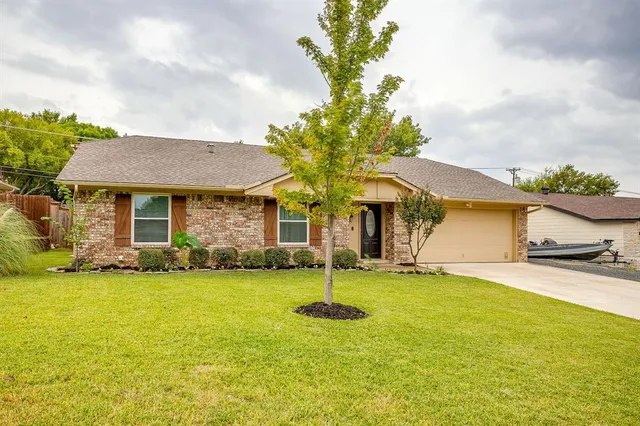 a front view of a house with a garden and tree