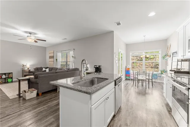 a kitchen with granite countertop a sink stove and wooden floor
