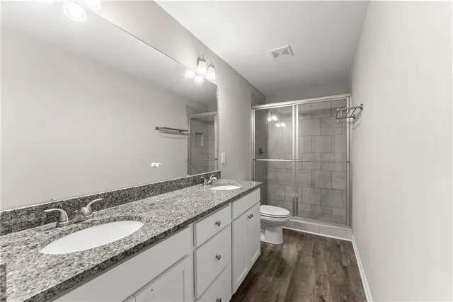 a bathroom with a granite countertop sink a toilet and shower