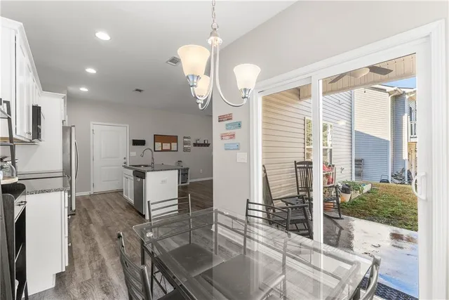 a kitchen with stainless steel appliances kitchen island granite countertop a stove a refrigerator a sink a dining table and chairs with wooden floor