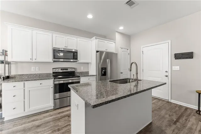 a kitchen with stainless steel appliances granite countertop a sink a stove a refrigerator a microwave and cabinets
