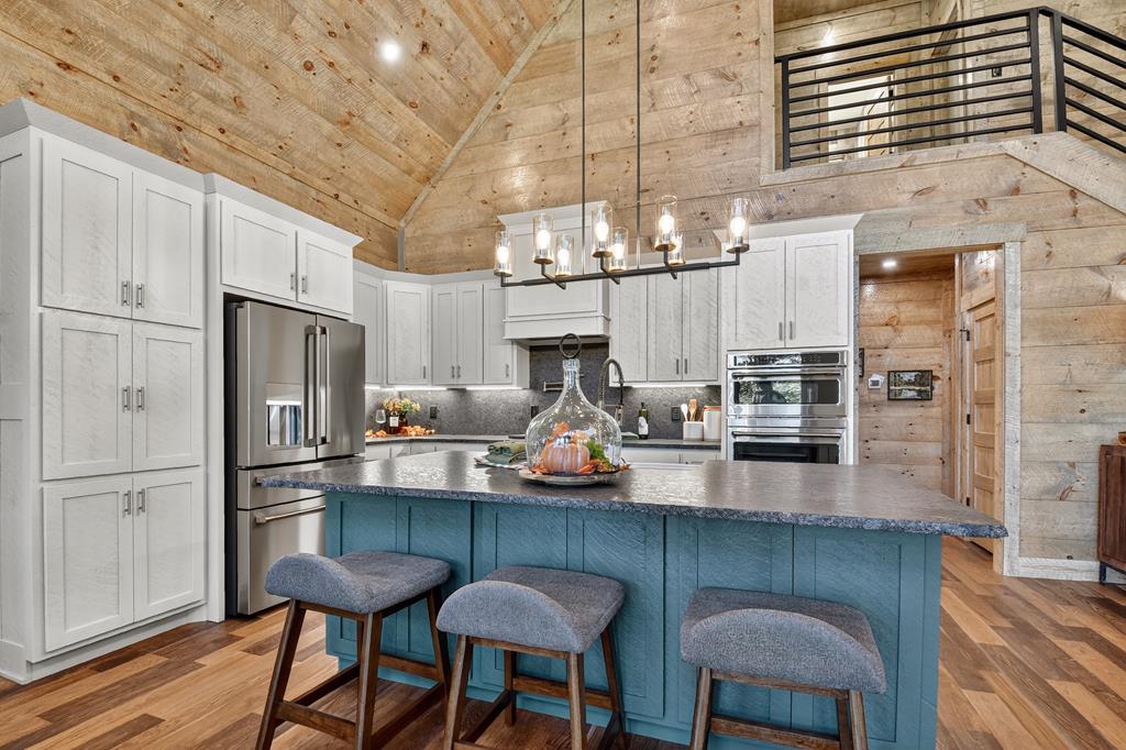 1204 Settler's Ridge Road Ellijay, GA 30540 - Photo 39 of 62 a kitchen with stainless steel appliances granite countertop a dining table chairs refrigerator and sink