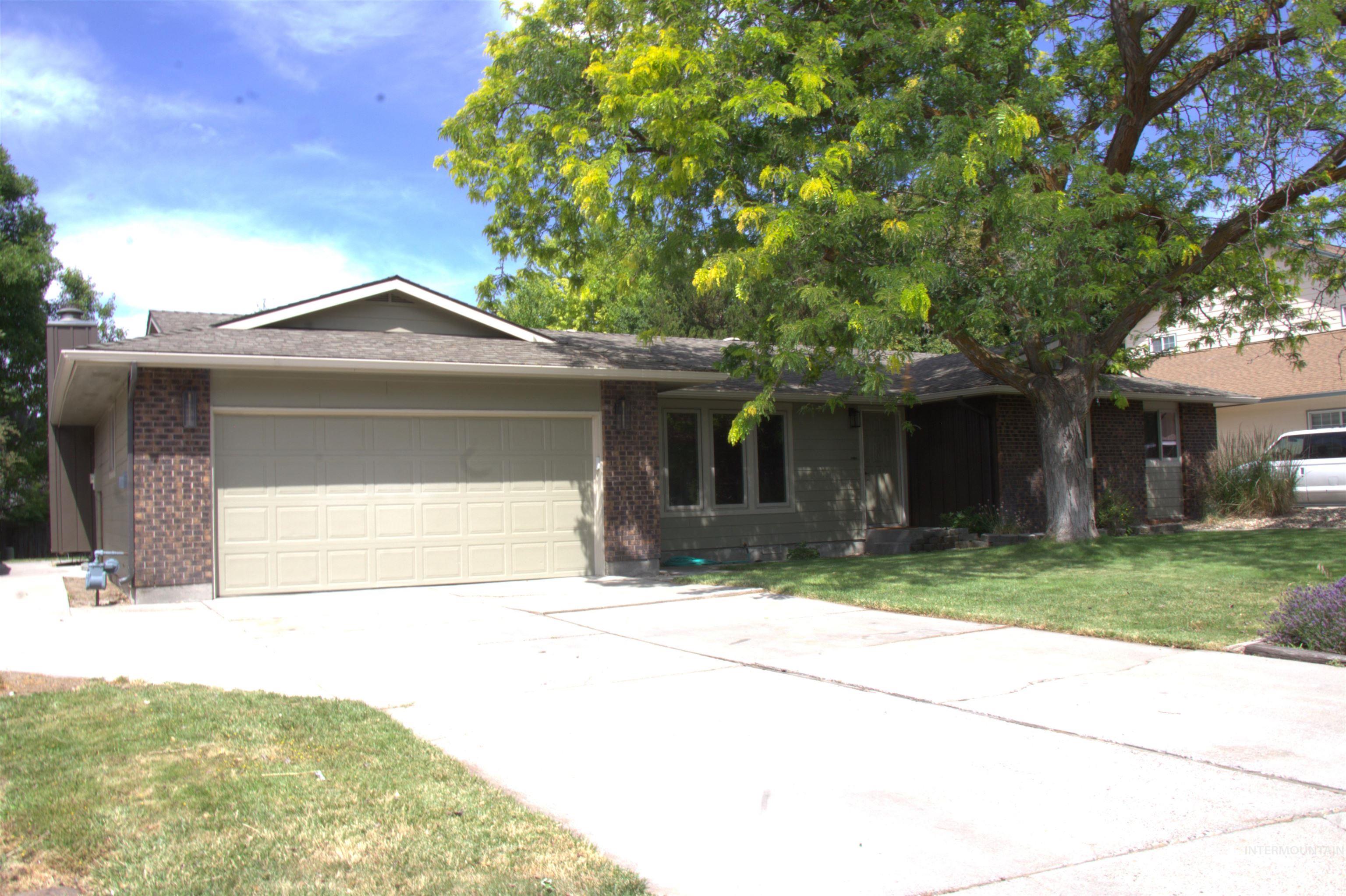 513 Ridge Way Ontario, OR 97914 - Photo 2 of 29 Ranch-style exterior featuring a two-car garage, brick accents, and a large mature shade tree