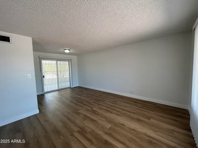 a view of an empty room with wooden floor and window