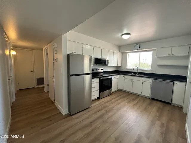 a kitchen with wooden floors stainless steel appliances and window