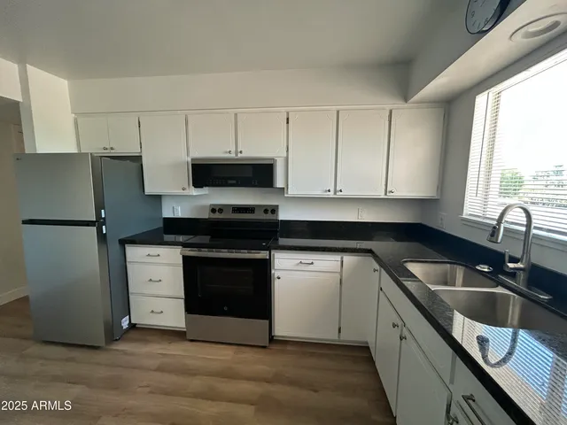 a kitchen with stainless steel appliances white cabinets a sink and a stove
