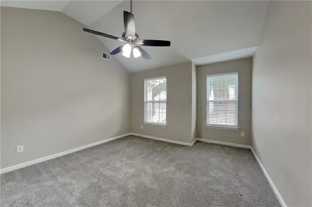 an empty room with chandelier fan and windows