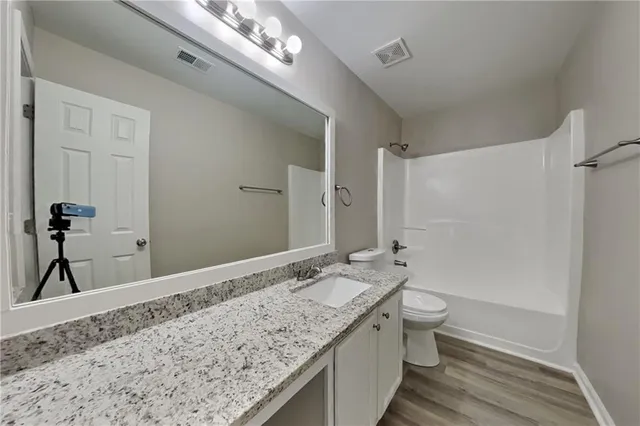 a bathroom with a granite countertop sink a toilet and shower