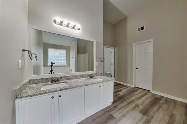 a bathroom with a granite countertop double vanity sink and mirror