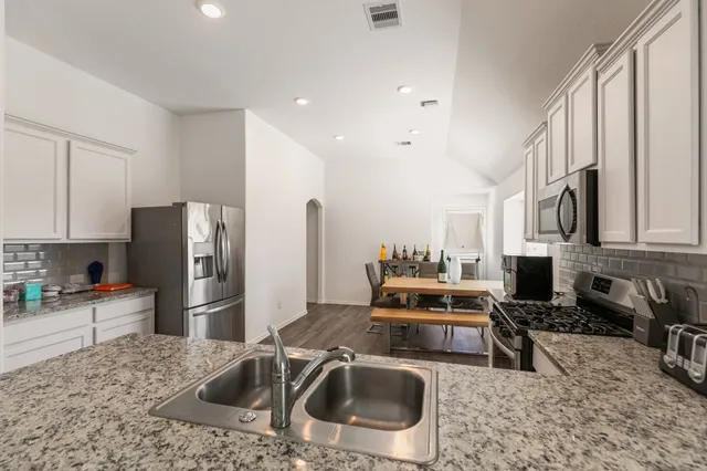 a kitchen with stainless steel appliances granite countertop a sink refrigerator and microwave