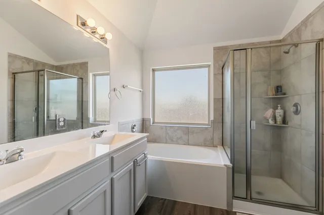 a bathroom with a tub sink shower and mirror