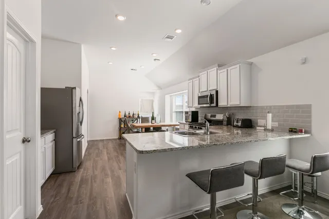 a kitchen with stainless steel appliances granite countertop a refrigerator and a stove top oven
