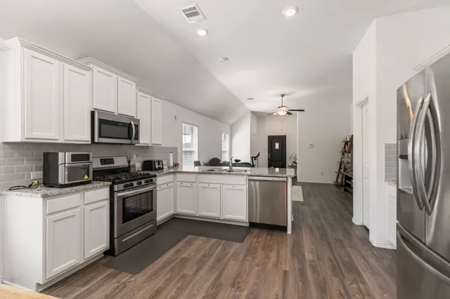 a kitchen with a sink wooden floor and stainless steel appliances