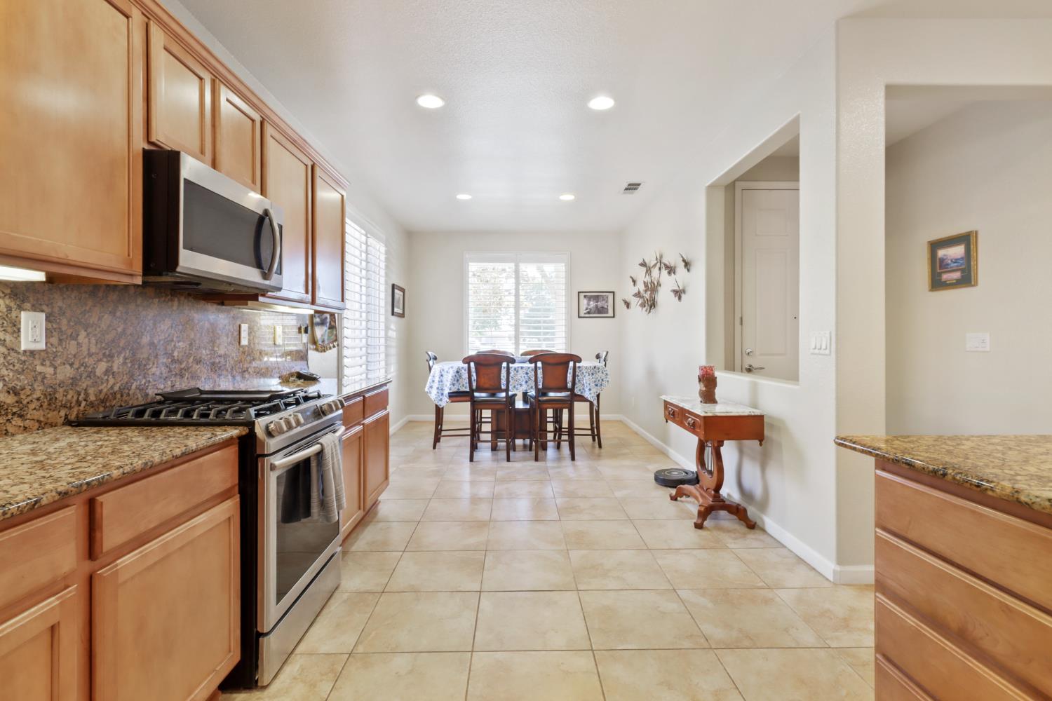 7401 Rothschild Court Elk Grove, CA 95757 - Photo 8 of 42 a kitchen with stainless steel appliances granite countertop a stove top oven a sink a dining table and chairs
