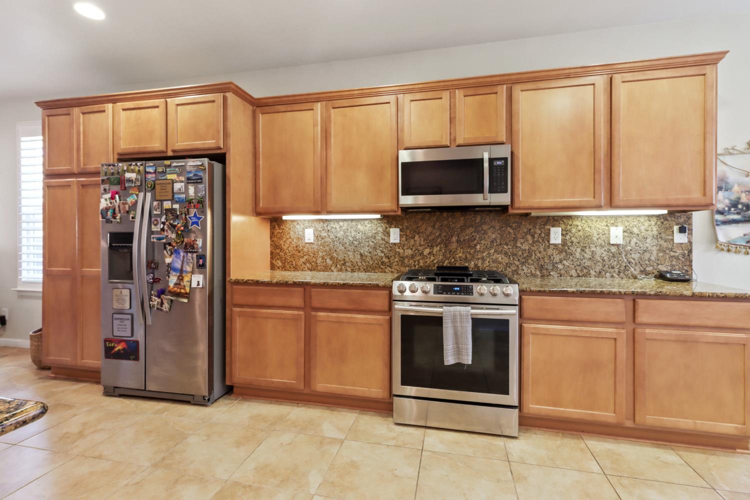 7401 Rothschild Court Elk Grove, CA 95757 - Photo 9 of 42 a kitchen with stainless steel appliances granite countertop a stove top oven a refrigerator and a sink