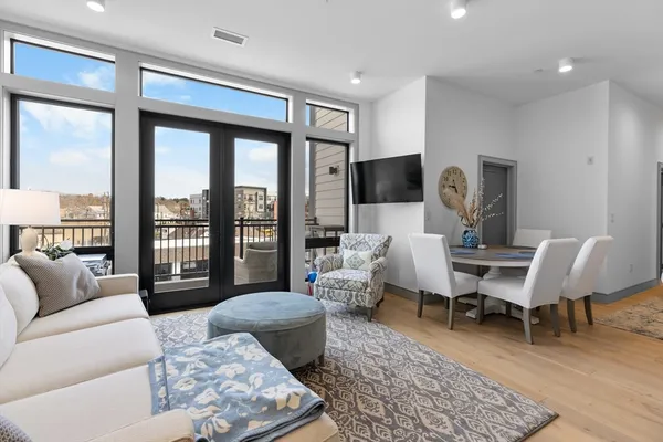 a living room with furniture floor to ceiling window and a flat screen tv