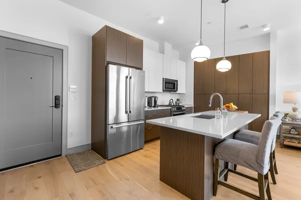 a kitchen with stainless steel appliances granite countertop a sink a stove a refrigerator and island with wooden floor