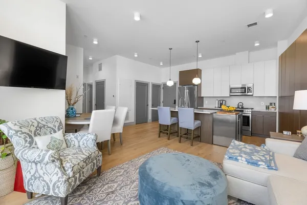 a living room with furniture kitchen view and a flat screen tv