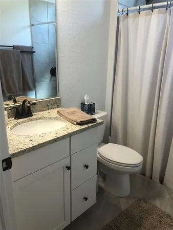 a bathroom with a granite countertop sink toilet and mirror