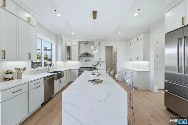 a large white kitchen with a large window a sink and stainless steel appliances