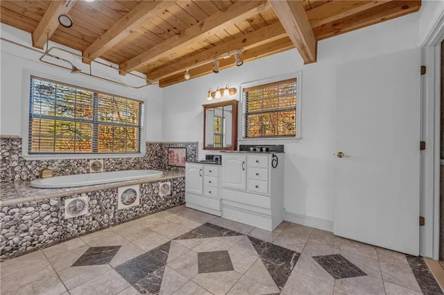 a bathroom with a granite countertop sink a mirror and a bathtub
