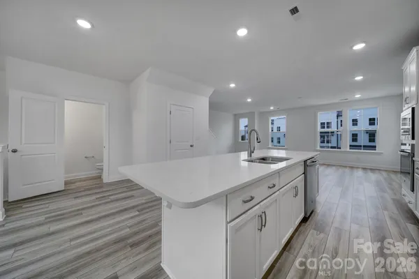 a open kitchen with kitchen island a sink dishwasher a stove and a refrigerator with wooden floor