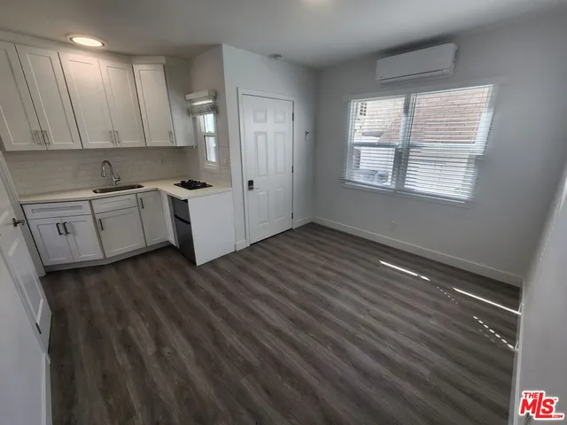 a kitchen with granite countertop white cabinets and wooden floor