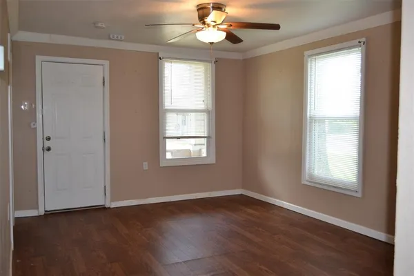 a view of an empty room with wooden floor and a window