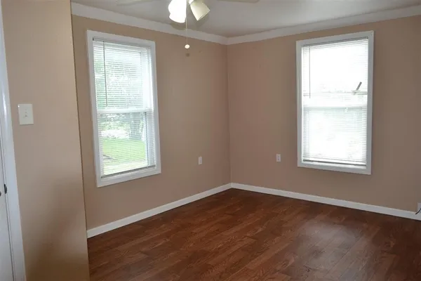 an empty room with wooden floor and windows