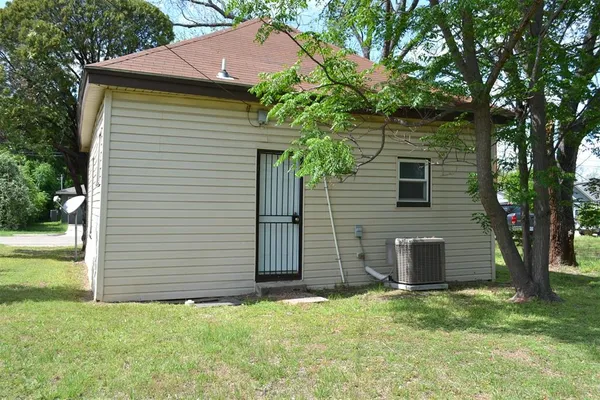 a backyard of a house with plants and a tree