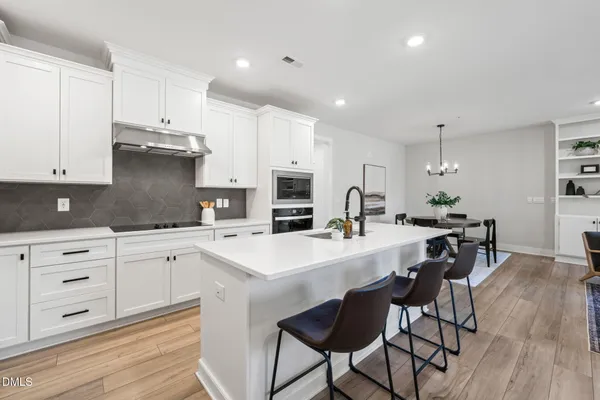 a kitchen with stainless steel appliances a stove a sink a stove a table and chairs