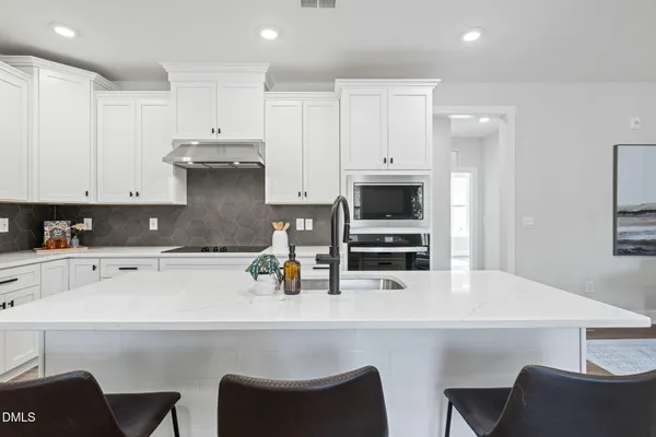 a kitchen with a table chairs microwave and cabinets
