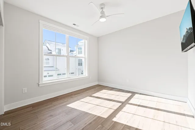 a view of an empty room with a window and wooden floor