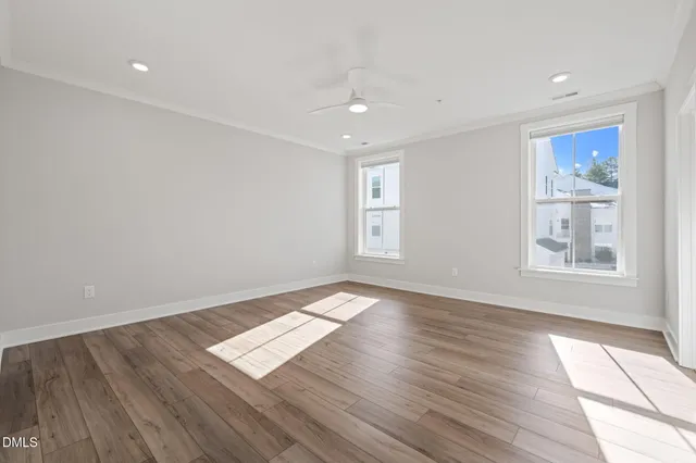 an empty room with wooden floor and windows