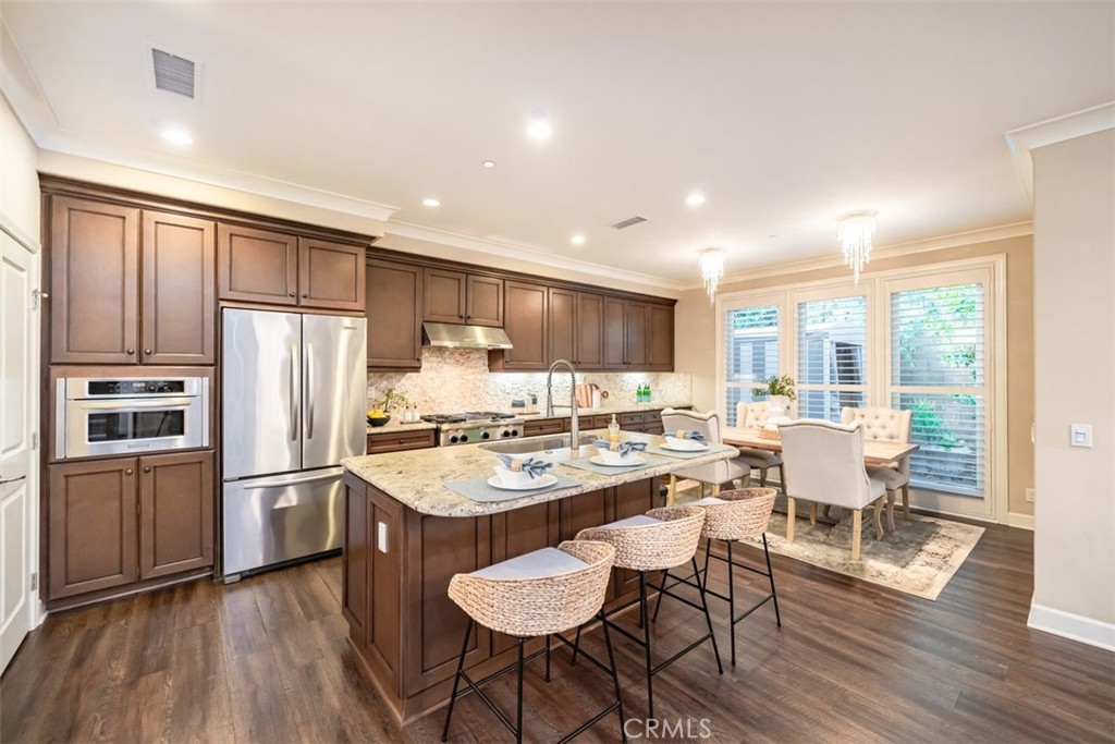 43 Lupari Irvine, CA 92618 - Photo 12 of 68 a kitchen with stainless steel appliances granite countertop a refrigerator stove microwave and a dining table with wooden floor