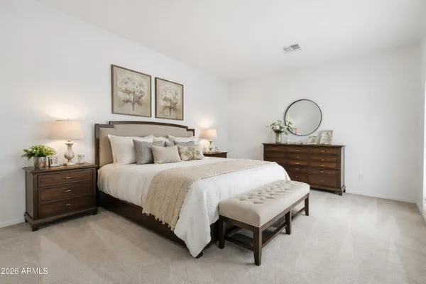 a bedroom with a bed a dresser and potted plants