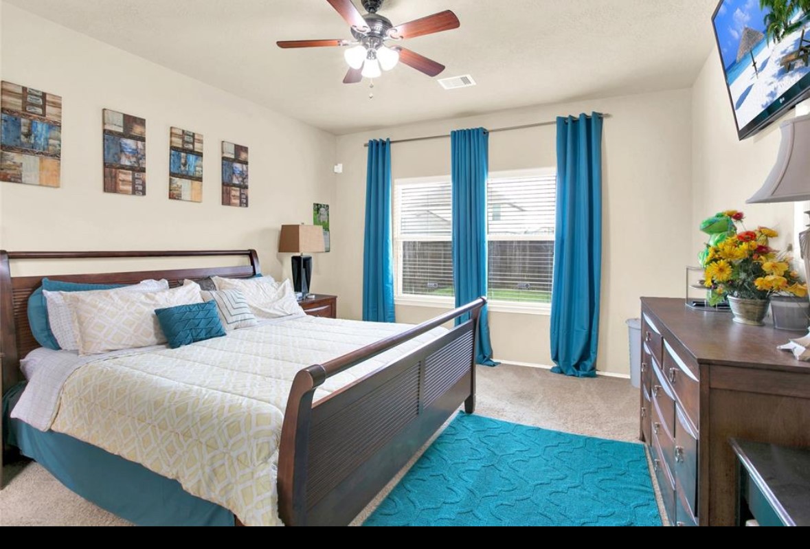 7035 Primrose Road Baytown, TX 77521 - Photo 4 of 18 a bedroom with a large bed and a chandelier