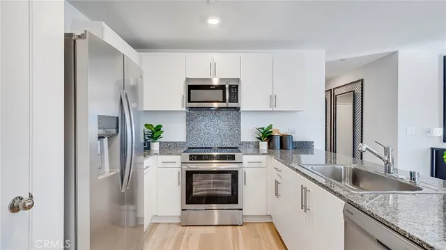 a kitchen with stainless steel appliances granite countertop a stove a sink and a refrigerator