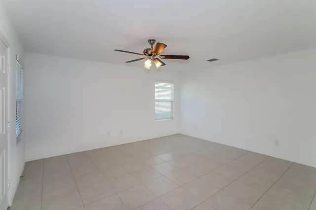 an empty room with a window and a ceiling fan