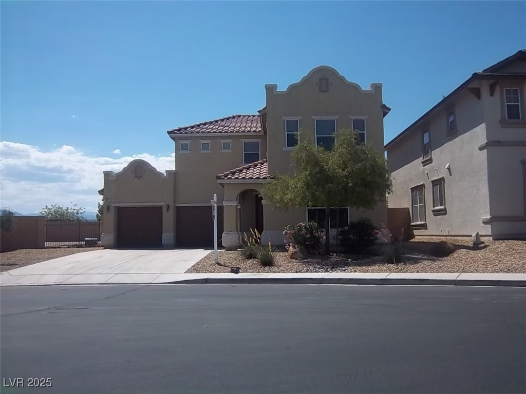 Mediterranean / spanish home featuring stucco siding, driveway, a garage, and a tile roof
