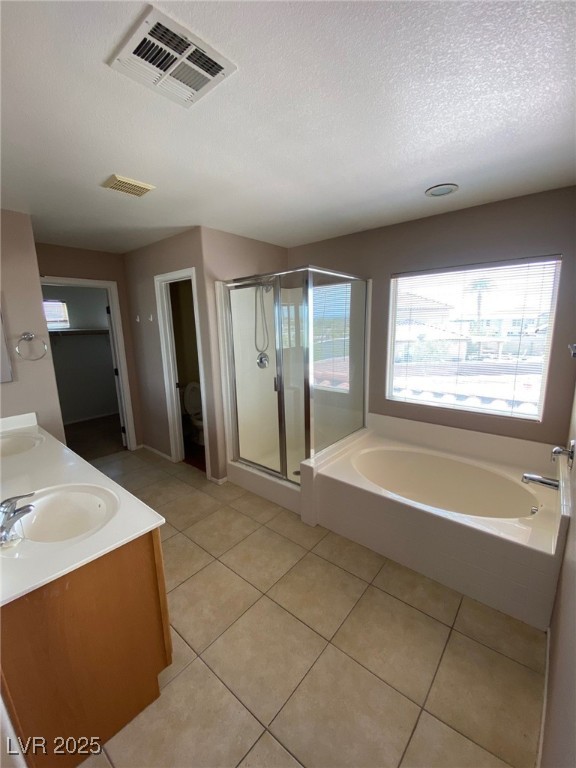 5817 Addy Lane, Unit N North Las Vegas, NV 89081 - Photo 25 of 32 Full bath with double vanity, a textured ceiling, a bath, a stall shower, and light tile patterned floors