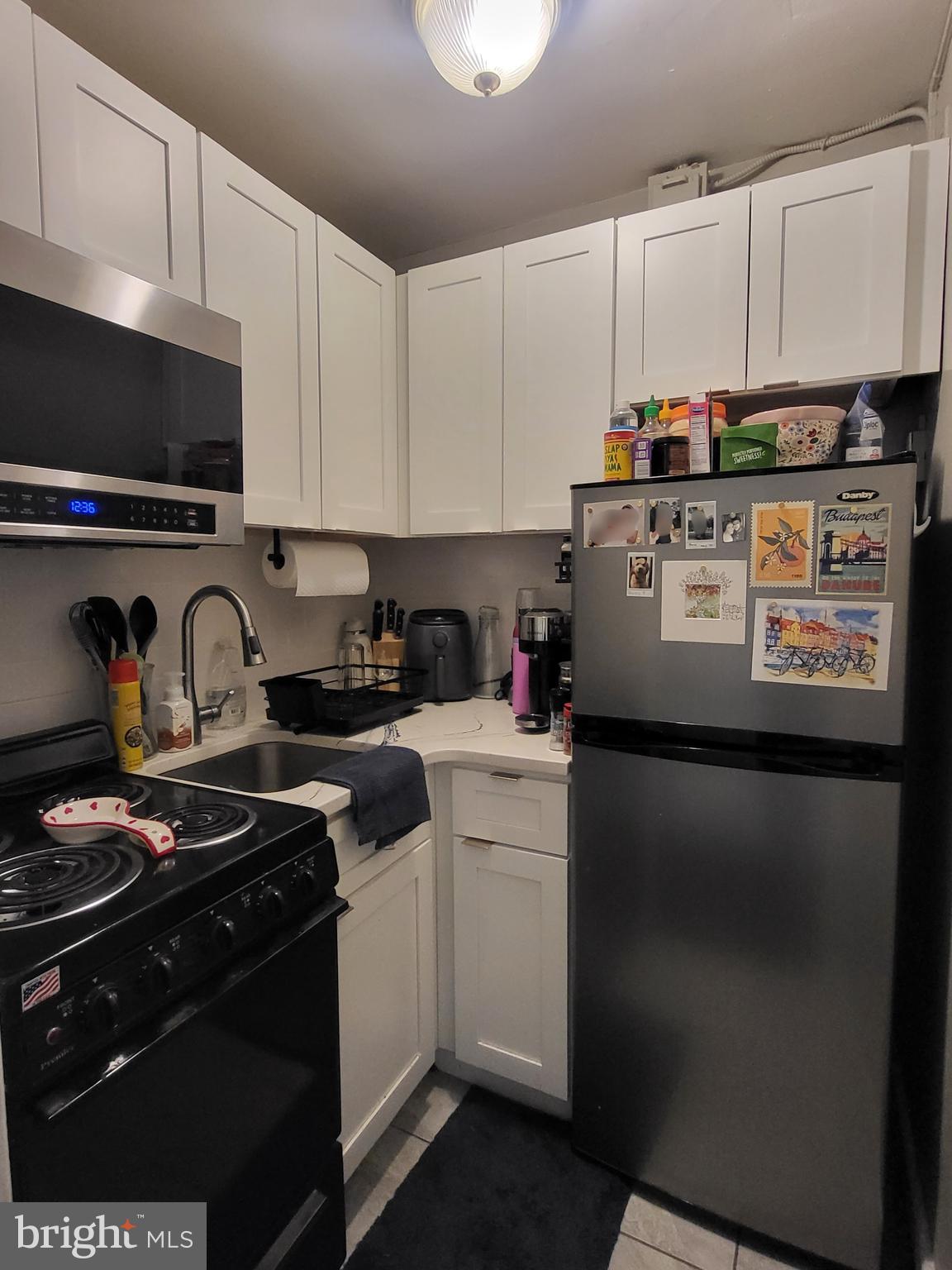 2031 Locust Street, Unit 1005 Philadelphia, PA 19103 - Photo 5 of 15 a utility room with stainless steel appliances granite countertop a stove a sink and a refrigerator
