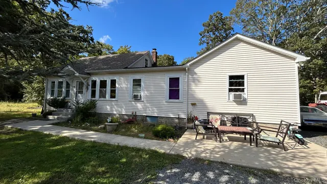 a view of a house with a yard chairs and table in a patio