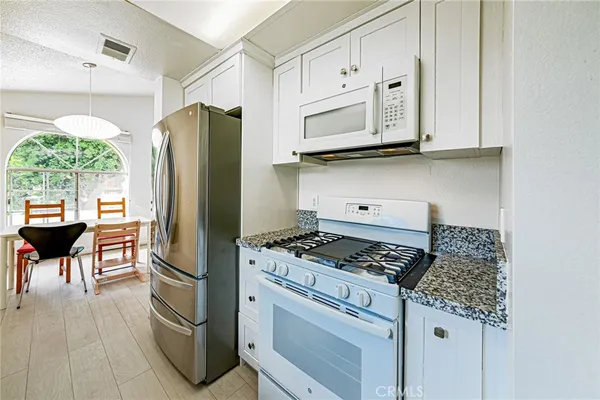 a view of a kitchen with wooden floor electronic appliances and windows