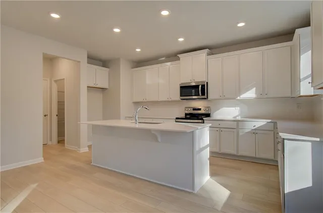 a kitchen with kitchen island white cabinets appliances and a sink