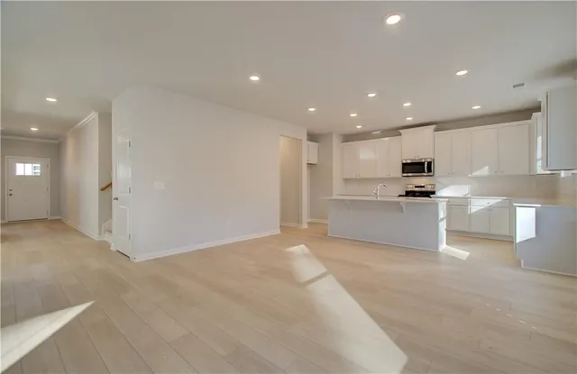 a view of kitchen with kitchen island a sink a stove and white cabinets