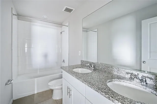 a bathroom with a granite countertop sink a toilet a mirror and shower