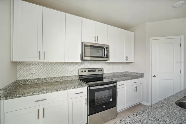 a kitchen with granite countertop white cabinets and stainless steel appliances