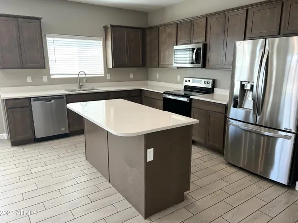 a kitchen with stainless steel appliances kitchen island granite countertop a refrigerator a sink a stove a microwave and island