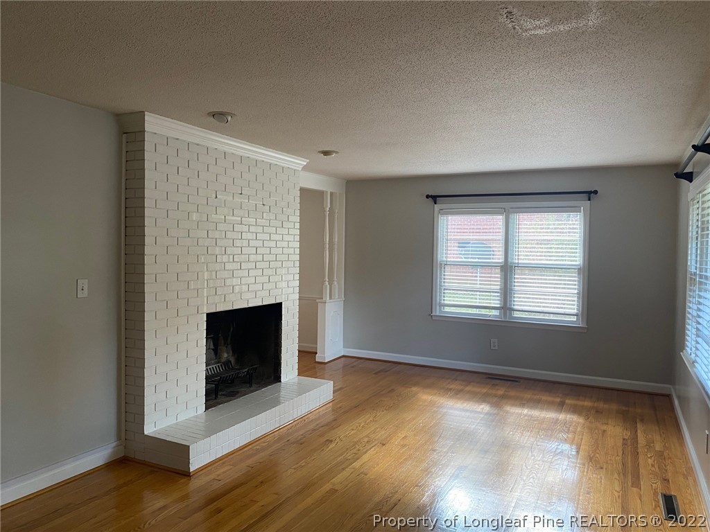 1811 Lyon Road Fayetteville, NC 28303 - Photo 10 of 27 a view of an empty room with wooden floor fireplace and a window